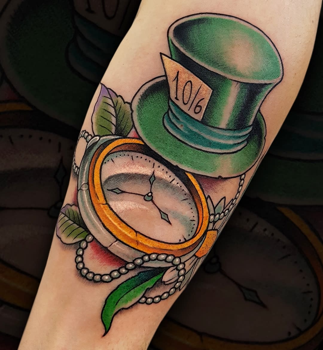 Vibrant tattoo of the Mad Hatter's green hat with a pocket watch, adorned with pearls and leaves